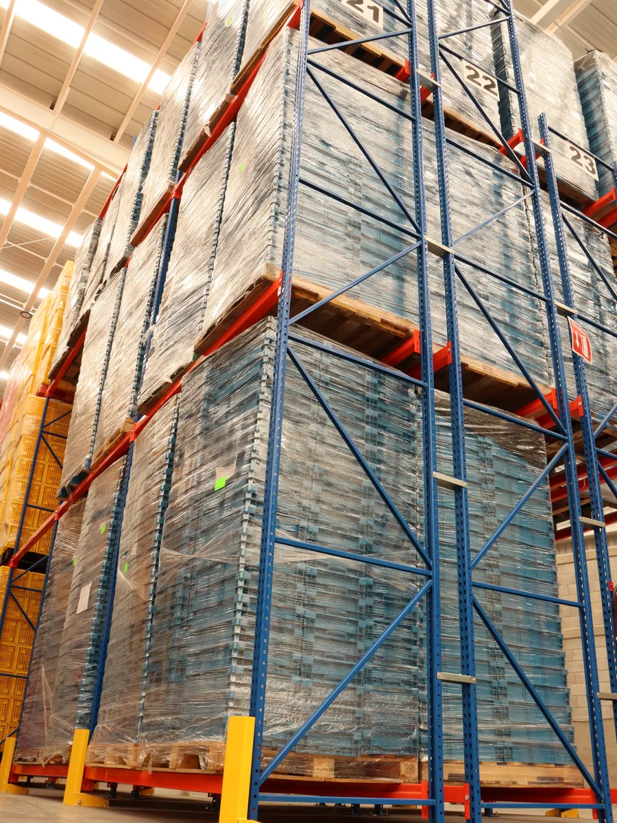 Racks del almacén de Europlast cargados de cajas de plástico apiladas y emplayadas sobre tarimas